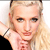 Pixelated close-up of a person with light-colored hair, dark eyes, and a neutral expression, wearing a dark top and a silver bracelet on the left wrist.