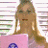 Pixelated image of a person with long light brown hair wearing a pink top, standing against a white background with horizontal colored stripes.