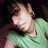Pixelated image of a person with light skin tone wearing a green shirt, dark hair visible against a black background.