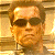 Pixelated image of a person with short brown hair wearing dark sunglasses and a light-colored shirt against a warm-toned background.
