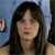 A pixelated close-up of a person with long dark hair and light skin, wearing a sleeveless top against a blue background with partial visible elements.