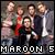Pixelated group of five people in formal attire with one person holding a red object, text "MAROON 5" at bottom.