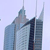 Pixelated image of modern skyscrapers with sharp spires against a light blue sky, featuring a central dark vertical structure and lighter blue and gray building facades.