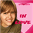 A pixelated image shows a person with light brown hair and a dark green shirt holding a pink sign that reads 'IN LOVE' in red text.