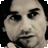 Pixelated grayscale portrait of a person with short dark hair, neutral expression, and visible facial features including eyes, nose, mouth, and beard stubble.
