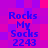 Pixelated text 'Rocks My Socks 2243' in blue on a purple-pink gradient background with four identical arrangements