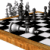 Animated chessboard with black and white squares, brown wooden border, and dark gray knight horse pieces in motion.