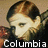 Pixelated portrait of a person with light skin and brown hair, wearing a dark jacket, with 'Columbia' text below.