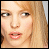 A pixelated of six showing a woman with blonde hair and light skin, her mouth opening in while text appears across the bottom