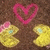 A static pixelated image shows a pink heart outline above two yellow circular shapes with light blue spots on brown background.