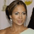 Pixelated close-up of a person with dark hair styled in an updo, wearing large silver hoop earrings and a light-colored garment, against a blurred background with a yellow shape.