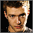 Pixelated image of a person with short brown hair and light skin, next to a white displaying 'i' above a gray heart symbol and the word 'justin' in multicolored block letters