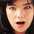 A pixelated close-up of a person's face with dark hair, showing eyes, nose, mouth, and skin tones against a dark background.