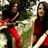 Two people in red and white striped clothing stand outdoors with greenery behind them, text in red pixelated font reads 'the white stripes are soo AMAZING!' on black background.