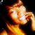 A pixelated image of a person with long brown hair holding a phone to their ear, displayed in a with visible pixelation and color shifts