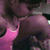 Pixelated image of a figure in dark clothing with pink accents, holding an object against a dark background.