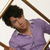 A person with short dark hair wearing a purple shirt, viewed from above against a light background.