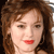 Pixelated close-up of a person with brown curly hair, light skin, and red lips against a dark background.