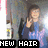 Pixelated image of a person with long brown hair wearing blue clothing, holding up two fingers in front of a blurred background with text reading NEW HAIR.