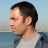 A 48x48 pixel buddy icon featuring a side-profile of a person with short dark hair wearing a light gray shirt and blue jacket, next to a yellow-and-black "Fear Factor" logo with stylized text.