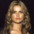 A static pixelated image of a person with long wavy brown hair, light skin, and red lips against a dark background.