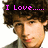 Pixelated image of a person with curly brown hair wearing a gray shirt, with pink text above the head reading "I Love....... NICK JONAS!" in two adjacent frames.