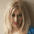 Static pixelated image of a person with light brown hair and red lips, wearing a blue garment on the right side, against a neutral background.