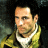 Static 48x48 pixel icon showing a close-up of a man's face with dark hair, wearing a yellow jacket over a white shirt and black tie against a dark background.