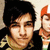 Pixelated static image shows two figures: one with dark hair and light clothing, another with orange hair in a stylized pose.