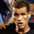 Pixelated close-up of a person's face with blurred background elements including blue and green shapes, likely from a sports context.