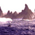Pixelated landscape with dark purple and brown mountain peaks against a light pink sky, reflecting in a purple water surface below.
