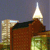 Pixelated image of a building with a tall spire against a dark blue sky, featuring brown brickwork and green-tinted windows.