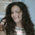 A static pixelated image of a person with long dark hair wearing a light-colored top against a blurred background.