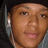 Pixelated close-up of a person's face with light brown skin tone, dark eyes, and visible ear with white earring against blurred background.