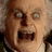 Pixelated close-up of a person with wide eyes and an open mouth, next to red pixelated text on a light background.