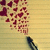 A static pixelated image shows a dark blue pen-like object emitting red and brown heart-shaped particles against a light yellow striped background.