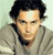 Pixelated portrait of a person with dark hair and a light-colored jacket against a pale background.