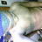 Pixelated static image with abstract shapes in blue, brown, green, and white tones, no discernible subjects or text.