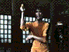 A person in an orange jumpsuit performs a sequence of martial arts movements against a dark -patterned background with light