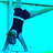 A figure in a black outfit performs a handstand on a blue background with green horizontal lines.