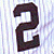 A split-screen image shows a dark brown number '2' on striped background and white interlocking 'NY' letters on blue background.