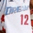 A pixelated image shows a white jersey with blue text and red numbers, partially visible on the right side.