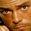Pixelated close-up of a person's face with warm brown and orange tones, showing eyes, nose, mouth, and partial hair in low-resolution detail.