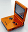 A pixelated orange handheld gaming device with a screen and buttons, angled against a light background.
