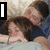 Two people lying in bed under a blanket, with one person's arm around the other; text overlays change between frames.
