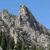 Pixelated landscape showing rocky mountain peaks with green vegetation below under a clear blue sky.