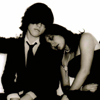 Two figures in black-and-white tones, one with dark hair and a tie, the other with long dark hair leaning toward the first figure.
