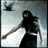 A woman with long dark hair in a sleeveless top and dark skirt stands with arms extended against a cloudy sky background, a bird flying above.