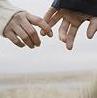 Two hands reach toward each other against a light background, fingers extended in mid-air.