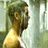 A man with short brown hair and a beard stands in a shower, facing left in the first frame and turning right in the second frame.